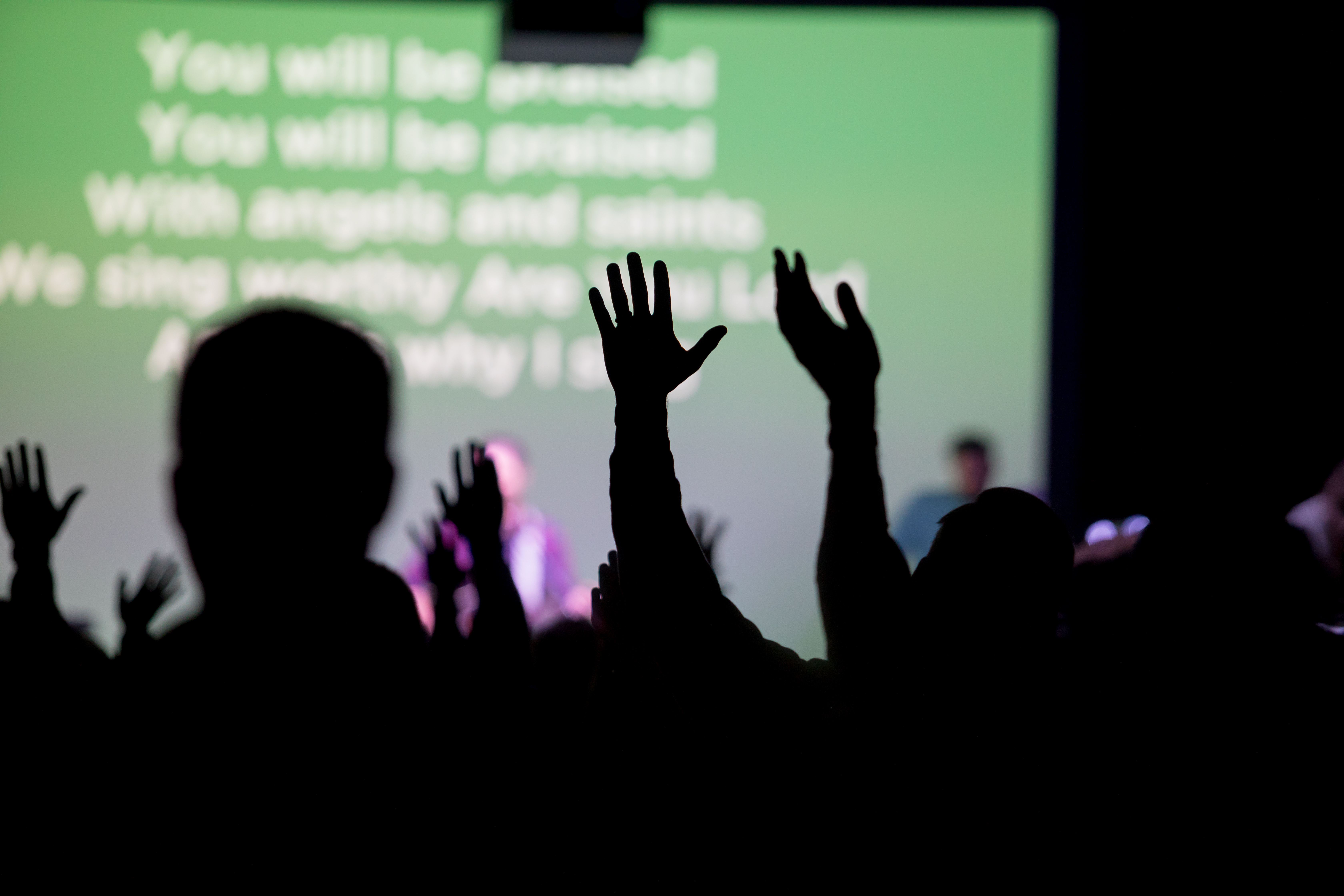 Christians raising their hands at a church worshipping Jesus during their religious service gathering.